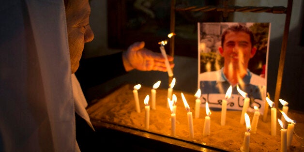 A Jordanian Christian lights a candle next to a picture of Jordanian pilot Lt. Muath al-Kaseasbeh, who is being held by Islamic State group militants, following Sunday prayers in Adir Roman Catholic Church, on the outskirts of Karak, Jordan, Sunday, Feb. 1, 2015. Jordan renewed an offer Sunday to swap Sajida al-Rishawi, an al-Qaida prisoner, for a fighter pilot held captive by the Islamic State group, a day after a video purportedly showed the militants beheading Japanese journalist Kenji Goto.