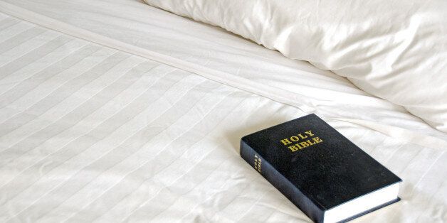 A bible laying upon an hotel bed.