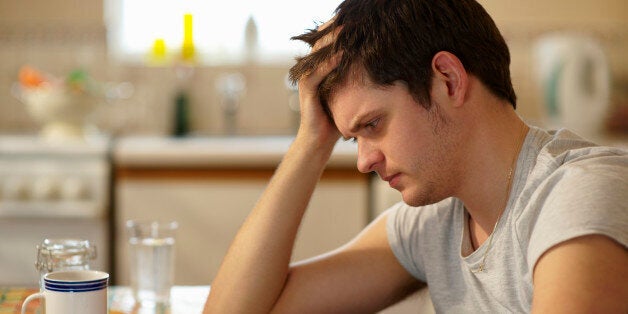 Young man holding head looking at receipts.