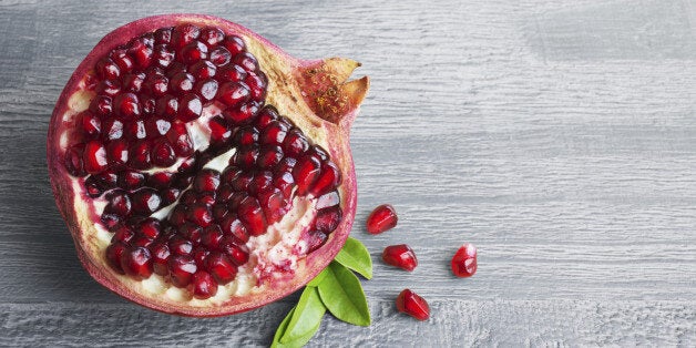 Juicy pomegranate fruit over wooden vintage table