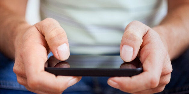 Hands of a casual man using a smartphone.