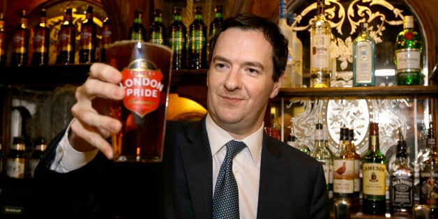 A man holds up a pint of beer during a visit to The Red Lion pub.