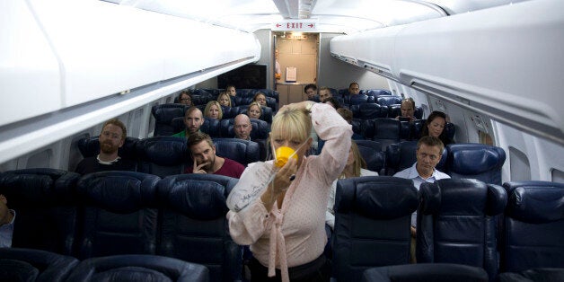 In this Sept. 10, 2014 photo, British Airways flight safety instructor Diane Pashley demonstrates the use of an oxygen mask during a British Airways Flight Safety training course at the airline's Cranebank training facility, near Heathrow airport in London. The half-day safety course, open to frequent fliers willing to pay $265, encourages passengers to be aware of their surroundings and familiarize themselves with what happens in an emergency. (AP Photo/Matt Dunham)