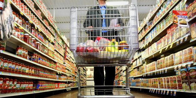 A man pushes his cart down a grocery aisle while shopping for groceries.