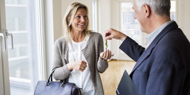 Happy male real estate agent giving keys to woman in new house