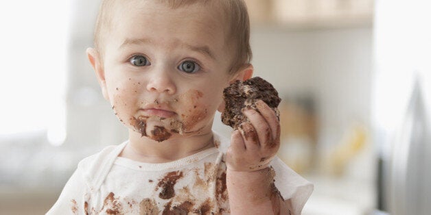 Messy Hispanic baby eating cake