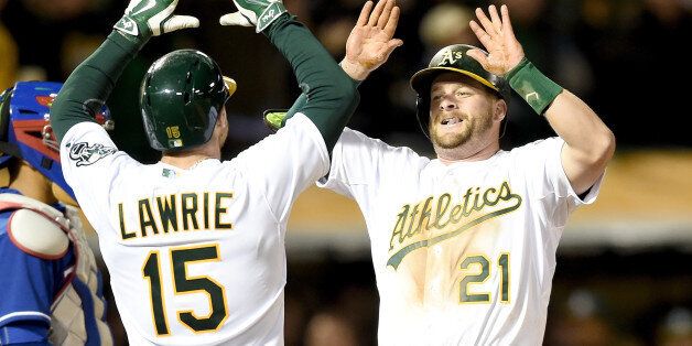 OAKLAND, CA - APRIL 06: Stephen Vogt #21 of the Oakland Athletics is congratulated by Brett Lawrie #15 after Vogt hit a three-run homer against the Texas Rangers in the bottom of the seventh inning on Opening Day at O.co Coliseum on April 6, 2015 in Oakland, California. (Photo by Thearon W. Henderson/Getty Images)