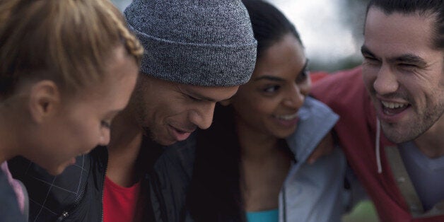 portrait of happy urban runners together at dusk, looking away from camera, landscape composition, two men aged 25 to 32, two women aged 26 to 32, full length action shot, urban landscape