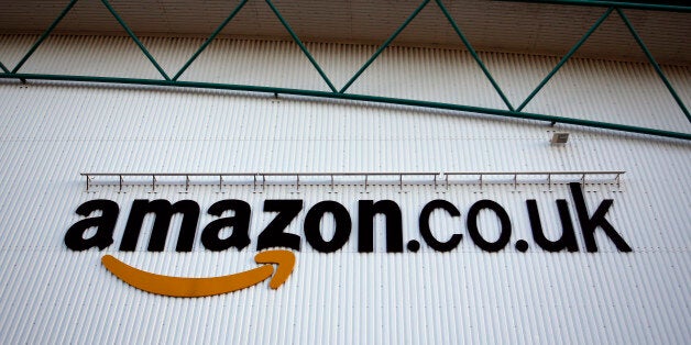 A logo sits on a wall outside the Amazon.co.uk Marston Gate 'Fulfillment Center,' the U.K. site of Amazon.com Inc. in Ridgmont, U.K., on Monday, Dec. 3, 2012. U.K. consumer confidence unexpectedly increased to an 18-month high in November as Britons become more optimistic about the economy and their finances, GfK NOP Ltd. said. Photographer: Simon Dawson/Bloomberg via Getty Images