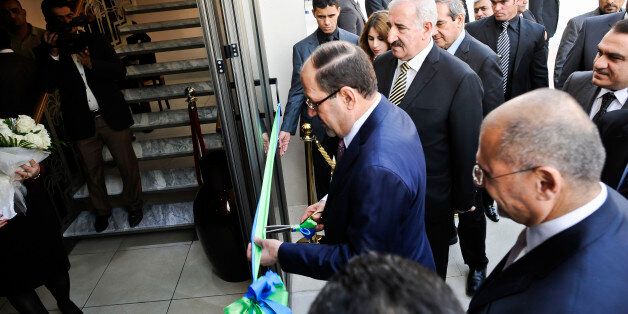 Iraq's Prime Minister Nouri Al-Maliki cuts a ribbon as he officially opens the first branch of British bank Standard Chartered, in, Baghdad, Iraq, in what is being billed as a significant milestone in its recovery.