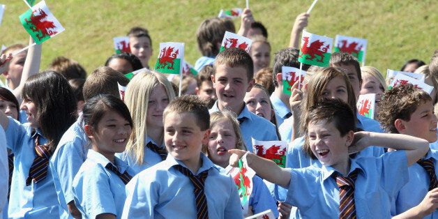 Children wave Welsh Flags as Prince Charles, Prince of Wales, makes a speech during a visit to Treorchy Comprehensive School. in Wales.