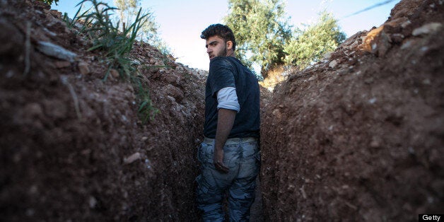 A Syrian rebel fighter throughout a trench dig by the rebels to hold a position, 100m far from the regime-controlled military base of Wadi Deif on June 14, 2013 in the village of Kfarruma in the Syrian province of Idlib. AFP PHOTO DANIEL LEAL-OLIVAS (Photo credit should read DANIEL LEAL OLIVAS/AFP/Getty Images)