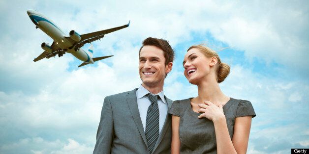 Outdoor portrait of business couple with flying airplane in the background.