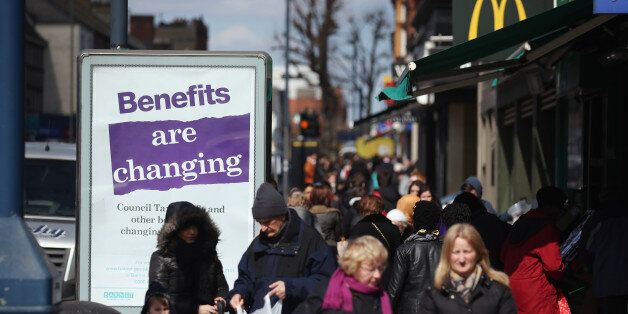 LONDON, ENGLAND - APRIL 02: Members of the public in North London walk past a poster informing of changes to the benefits and tax system that have come into force yesterday, on April 2, 2013 in London, England. The widespread changes include a cut in housing benefit payments for working-age social housing tenants whose property is deemed larger than they need and council tax support payments being administered locally. (Photo by Oli Scarff/Getty Images)
