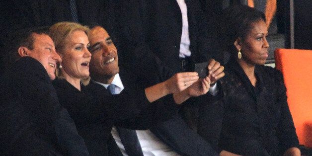 President Barack Obama (R) and British Prime Minister David Cameron pose for a selfie picture with Denmark's Prime Minister Helle Thorning Schmidt (C) next to US First Lady Michelle Obama (R) during the memorial service of South African former president Nelson Mandela at the FNB Stadium (Soccer City) in Johannesburg on December 10, 2013. Mandela, the revered icon of the anti-apartheid struggle in South Africa and one of the towering political figures of the 20th century, died in Johannesburg on