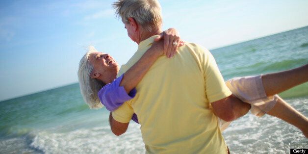 Senior man carrying his wife on the beach