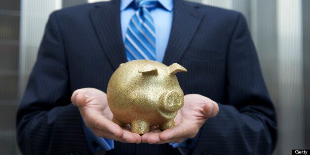 Businessman stands holding a golden piggy bank cradled in his hands