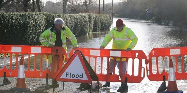 Workers from the Worcestershire Highways Department place barriers in front of a flooded road in Fladbury, Worcestershire.
