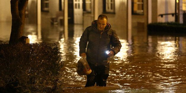 DORKING, UNITED KINGDOM - DECEMBER 24: A man wades through rising floodwater from the River Mole outside the Burford Bridge Hotel on December 24, 2013 near Dorking, England. Christmas plans have been badly affected for thousands of people after storms across the UK have resulted in flooding, power cuts and significant problems with transport infrastructure. (Photo by Peter Macdiarmid/Getty Images)