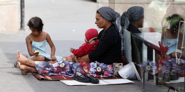 A Roma woman and her children begs place de la Bastille in Paris, on August 22, 2012. The French government seeks to end a row over its treatment of ethnic Roma migrants in a move that could result in Bulgarian and Romanian citizens being granted the right to work in France. AFP PHOTO KENZO TRIBOUILLARD (Photo credit should read KENZO TRIBOUILLARD/AFP/Getty Images)