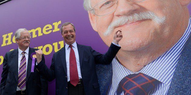 Leader of the UK Independence Party (UKIP) Nigel Farage (R) poses in front of a campaign poster for local UKIP candidate Roger Helmer (L) during his visit to Southwell, Newark upon Trent, central England on May 31, 2014. The visit by Farage was part of UKIP campaigning ahead of the upcoming by-election in the town. AFP PHOTO/ANDREW YATES (Photo credit should read ANDREW YATES/AFP/Getty Images)