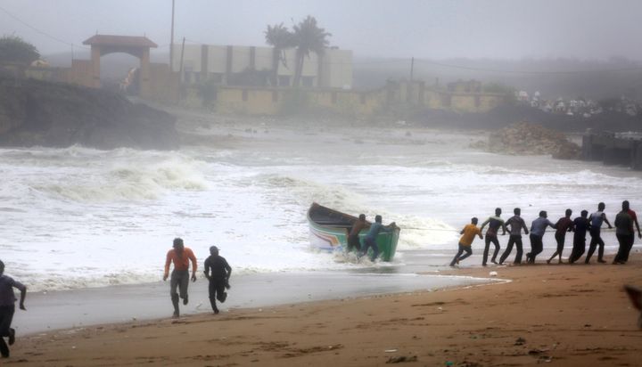 People try to pull back a fishing boat that was carries away by waves on the Arabian Sea coast as others run to take shelter in Veraval, Gujarat, on 13 June 2019. 