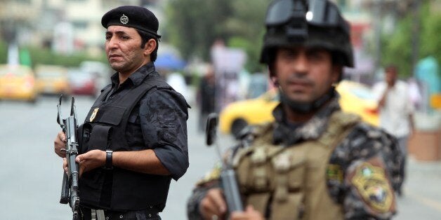 Iraqi policemen stand guard on a main road in Baghdad as Shiite Muslim pilgrims walk on May 20, 2013 towards the Imam al-Kadim shrine for a commemoration ceremony to be held this week amid a sharp increase in violence. Pilgrims converge on the seventh Imam's shrine in the Kadhimiya district of northern Baghdad to mark his death in 795 after being poisoned by Iraq's ruler then, Harun al-Rashid. AFP PHOTO/AHMAD AL-RUBAYE (Photo credit should read AHMAD AL-RUBAYE/AFP/Getty Images)