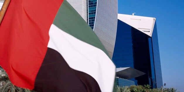 UAE, Dubai, national bank of Dubai seen from dhow on Dubai creek with UAE flag in the foreground.