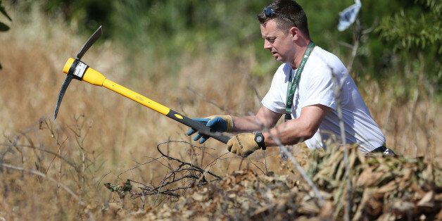 A British police officer clears an area of wasteland during the search for evidence of Madeleine McCann, in the town of Praia da Luz in Portugal where she went missing seven years ago.