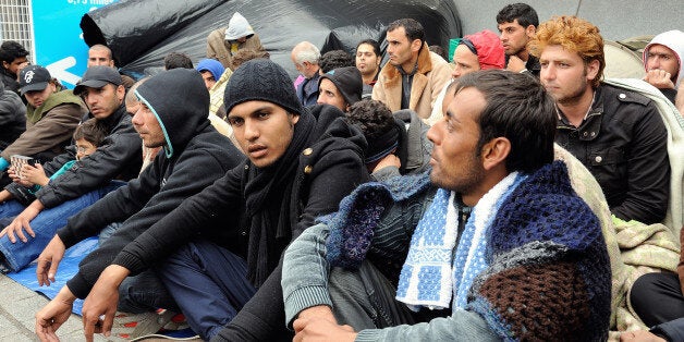 Syrian refugees gather at the Calais port, a departure point for ships bound for Britain, on October 4, 2013. France offered some 60 Syrians the right to seek asylum after the refugees occupied a key point in the Channel port of Calais in a desperate bid to get to Britain. A three-member team from Britain's border police was meanwhile on its way to Calais to hold discussions with the refugees, said Denis Robin, the prefect of the Pas-de-Calais region. AFP PHOTO / PHILIPPE HUGUEN (Photo cr