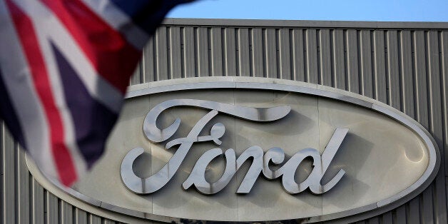 A Ford logo is seen on a stamping operations building near a Union Jack flag at the Ford Motor Co. automobile...