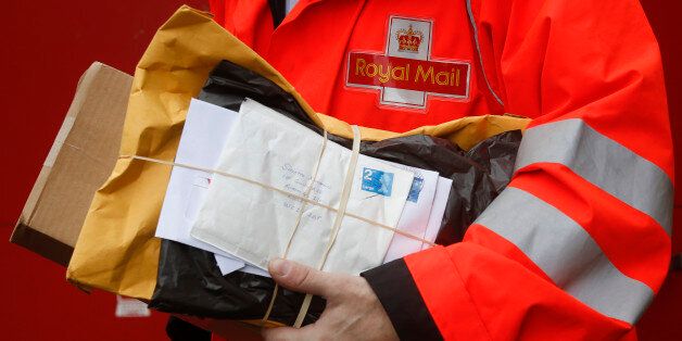 A Royal Mail Group Ltd. employee carries a bundle of letters during his delivery round in London, U.K. on Thursday, May 30, 2013. The U.K. government appointed UBS AG and Goldman Sachs Group Inc. as joint global coordinators and joint bookrunners for the sale of Royal Mail Group Ltd., the state-owned postal service. Photographer: Simon Dawson/Bloomberg via Getty Images