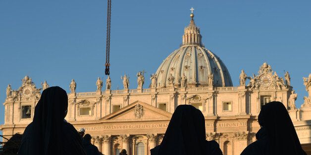 Nuns watch during the setup of the traditional Christmas tree on St Peter's square on December 5, 2013 at the Vatican. The tree, that was cut in Regensburg, Germany, is 25 metres tall, weights 7,2 tons and is 45-year-old. AFP PHOTO / GABRIEL BOUYS (Photo credit should read GABRIEL BOUYS/AFP/Getty Images)