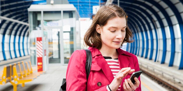 Woman texting while waiting for train.