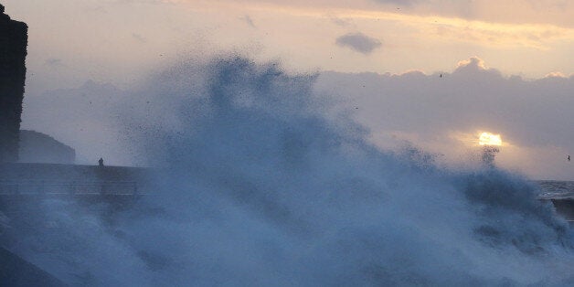 A man looks out from the beach at sunrise at West Bay during stormy weather on January 3, 2014 in Dorset, England.