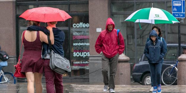 Office workers and tourists are pictured in the rain outside St Paul's cathedral in central London this afternoon.