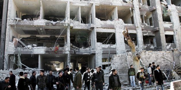 Syrian security officers gather in front the damaged building, attacked by al-Qaida-style group Jabhat al-Nusra, a shadowy group of veterans of jihad in Iraq, Libya and elsewhere