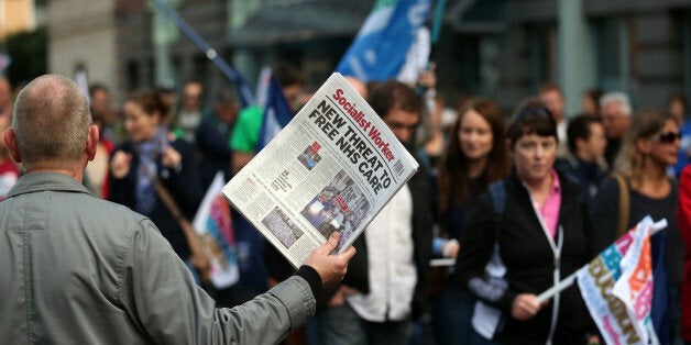 BRISTOL, ENGLAND - OCTOBER 17: Striking teachers and protestors march past a man selling a Socialist Worker newspaper as they take part in a rally organised by the NUT and NASUWT unions on October 17, 2013 in Bristol, England. As part of a continuing campaign of regional strikes involving members of the NUT and NASUWT unions, thousands of schools are closed across many areas of England today, as teachers take part on a one-day strike over pay, pensions and jobs. (Photo by Matt Cardy/Getty Imag