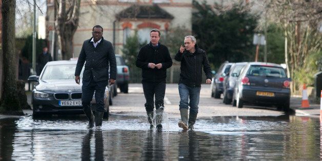 Prime Minister David Cameron meets with resident Ray Connerlley(right) and Kwasi Kwarteng, the MP for Spelthorne, on a flooded Guildford Street in Staines-upon-Thames.