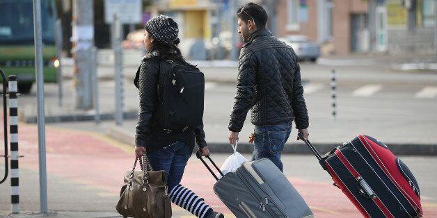 SOFIA, BULGARIA - DECEMBER 07: A young Roma couple walk with suitcases outside the main bus station on December 7, 2013 in Sofia, Bulgaria. Restrictions on the freedom of Bulgarians and Romanians to work in the European Union are due to run out by December 31, though several EU leaders, including British Prime Minister David Cameron, are considering imposing temporary restrictions to cut the flow of Romanians and Bulgarians arriving in EU countries. Many EU nations have voiced concern over too