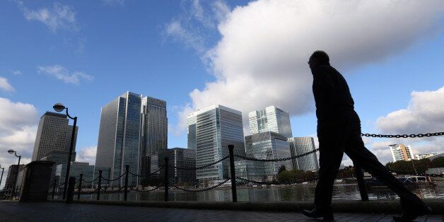 A pedestrian passes bank headquarters and commercial real estate offices in the Canary Wharf business and financial district in London, U.K., on Tuesday, Nov. 19, 2013. Bank employees used their mobile phones and instant-messages to transmit details of impending client orders to individuals working from rented trading desks in offices on the outskirts of the U.K. capital, who then made bets on their behalf, according to three traders who said they had witnessed the practice over a period of year