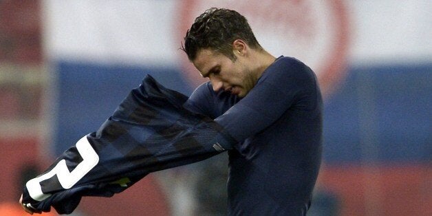 Manchester United's Dutch forward Robin van Persie takes off his jersey after losing the round of 16 Champions League football match Olympiakos vs Manchester United at Karaiskaki Stadium in Athens on February 25, 2014. AFP PHOTO / ARIS MESSINIS (Photo credit should read ARIS MESSINIS/AFP/Getty Images)