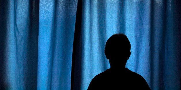 The Silhouetted Shape Of A 13yr Old Boy,Standing In Front Of Blue Coloured Drawn Curtains. (Photo by: Universal Education/Universal Images Group via Getty Images)