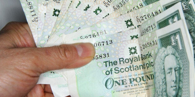 GLASGOW, SCOTLAND - JANUARY 30: In this photo illustration, a man holds Scottish one pound bank notes on January 30, 2014 in Glasgow, Scotland. The Governor of the Bank of England Mark Carney, said yesterday during a speech in Edinburgh, that an independent Scotland would need to give up some power to make a currency union with the rest of the UK work. (Photo Illustration by Jeff J Mitchell/Getty Images)