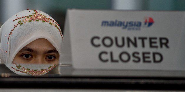 A Malaysia Airlines employee sits behind a closed ticket counter at the Kuala Lumpur International Airport in Sepang on July 20, 2014. Malaysia Airlines said it would offer full refunds to customers who want to cancel their tickets in the wake of the MH17 disaster, just months after the carrier suffered another blow when flight MH370 dissapeared. AFP PHOTO/ MANAN VATSYAYANA (Photo credit should read MANAN VATSYAYANA/AFP/Getty Images)