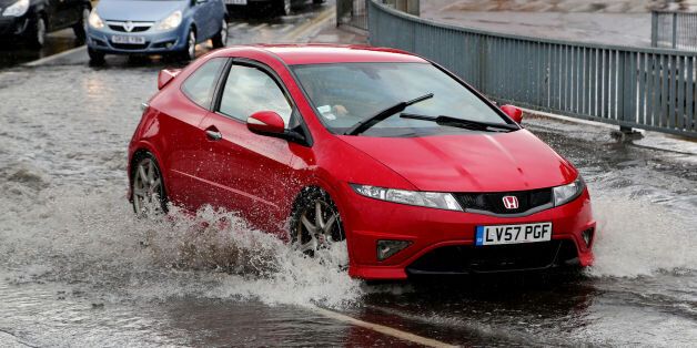 Cars pass through a flash flood following a heavy rain shower in Maidstone, Kent.
