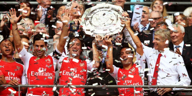 LONDON, ENGLAND - AUGUST 10: Santi Cazorla of Arsenal holds up the trophy watched by Arsene Wenger, manager of Arsenal after the FA Community Shield match between Manchester City and Arsenal at Wembley Stadium on August 10, 2014 in London, England. (Photo by Clive Mason/Getty Images)