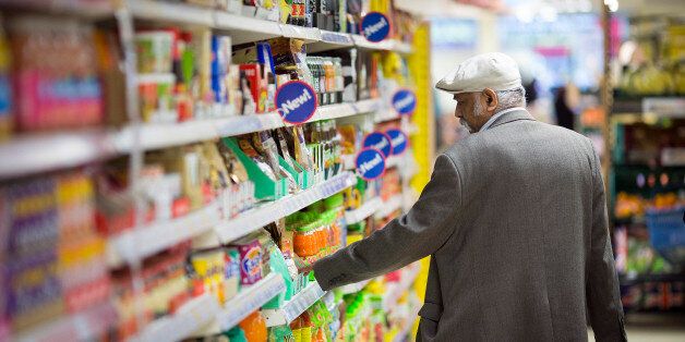 A customer looks at the price of an item displayed for sale on a shelf inside a Tesco Metro store