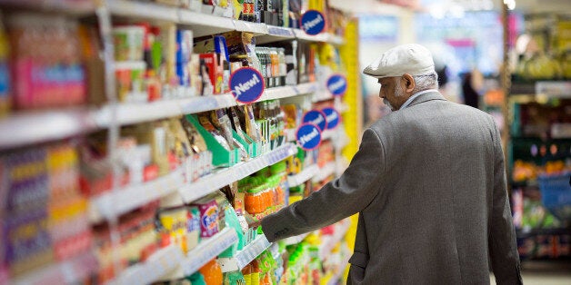 A customer looks at the price of an item displayed for sale on a shelf inside a Tesco Metro store