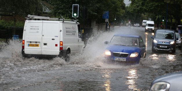 Traffic drives through a flooded road in Lewisham in south east London as a third of a month's rain could fall in just a few hours today as torrential downpours and thunderstorms hit parts of the UK.